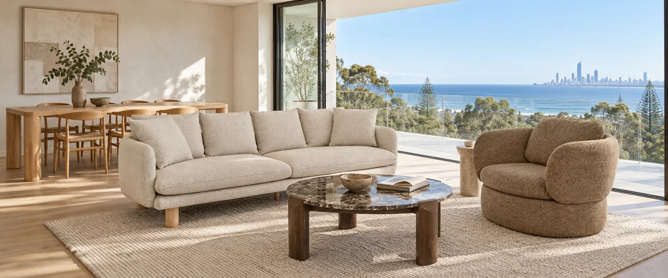 Almond sofa, brown marble coffee table and toffee armchair, with an ash dining table and coastal views