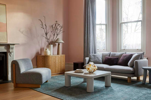 Tepih Dune Rug in Sacramento, styled in a living room with a grey sofa and pale coffee table against pink walls