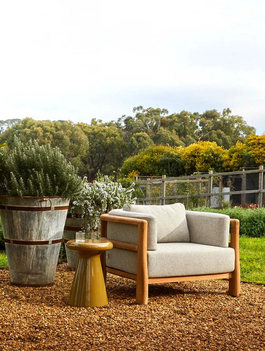 Andalusian Platform Grand End Table beside a timber-framed armchair on a gravel garden terrace