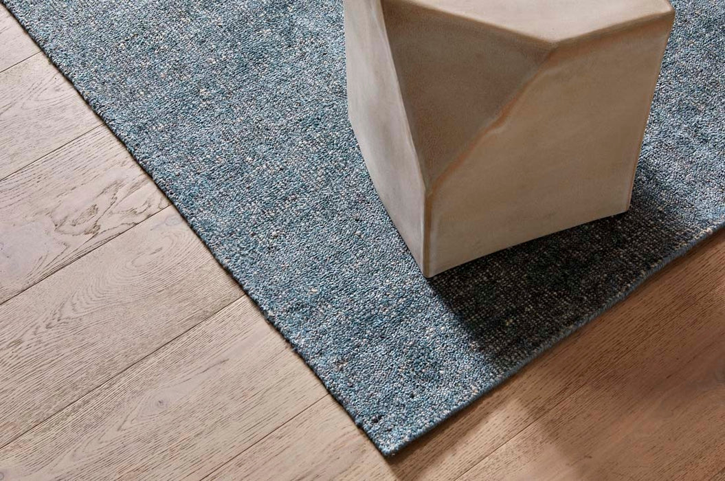 Tepih Dune Rug in Sacramento, a corner on timber floorboards beside a stone side table
