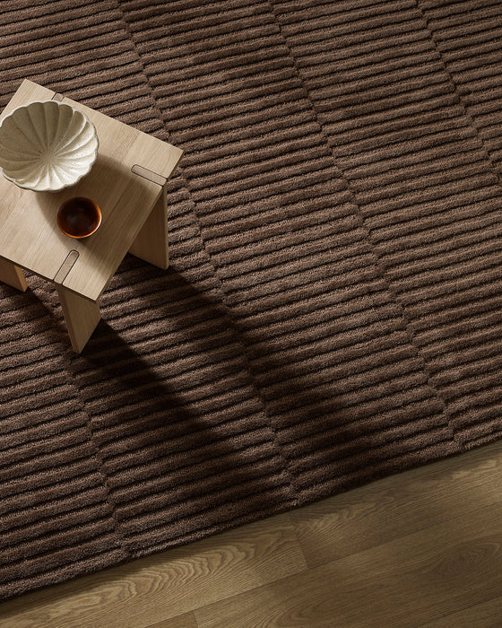 Anni Floor Rug in Chocolate, seen from above with a pale timber side table, showing the ribbed texture