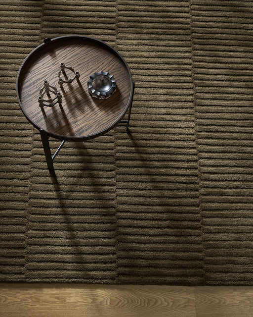 Anni Floor Rug in Mangrove, seen from above with a round dark side table, showing the ribbed pile