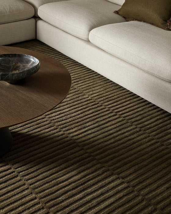 Anni Floor Rug in Mangrove, under a round timber coffee table beside a cream sofa, showing the ribbed pile