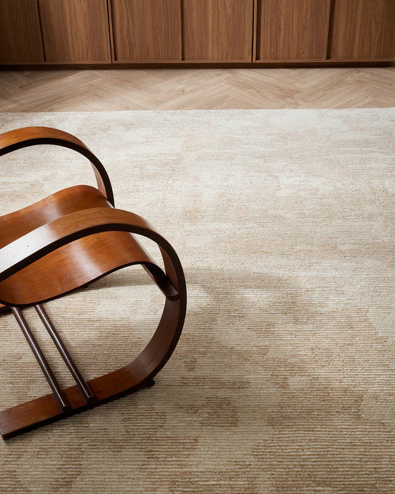 Beckett Floor Rug in Straw, with a bentwood timber armchair on a herringbone floor