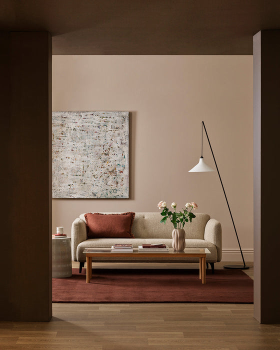 Bastion Floor Rug in Claret, styled in a living room with a cream sofa, timber coffee table and floor lamp