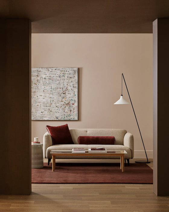 Bastion Floor Rug in Claret, under a timber coffee table and cream sofa with red cushions in a living room