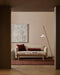 Bastion Floor Rug in Claret, under a timber coffee table and cream sofa with red cushions in a living room