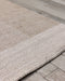 Bedrock Floor Rug in Sand, close up of a corner on timber decking, showing the woven texture