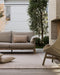 Bedrock Floor Rug in Sand, on a courtyard deck with an outdoor sofa and woven lounge chair