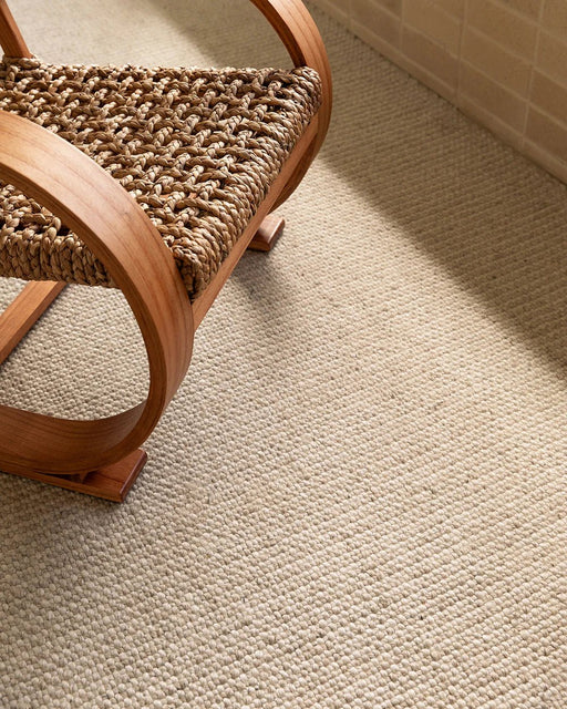 Kansas Floor Rug in Oat/Natural, close view beside a woven armchair with a bentwood frame