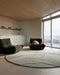 Edgewater Round Floor Rug in Pistachio, in a living room with dark green lounge chairs and a kitchen behind