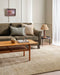 Fairbanks Floor Rug in Limestone, under a timber coffee table and olive sofa with a table lamp