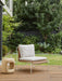 Blossom Armchair on a timber deck in a leafy garden beside a sculptural stone side table
