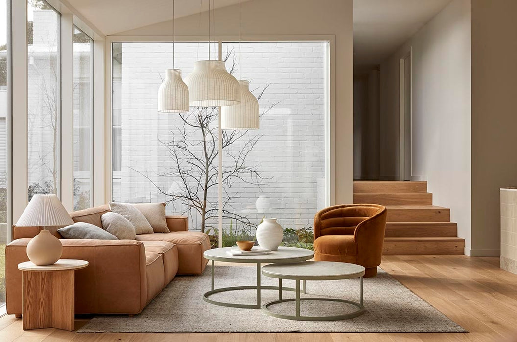 Tepih Dune Rug in Oatmeal, styled in a living room with a tan leather sofa and round coffee tables