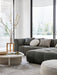 Tepih Dune Rug in Oatmeal, under a dark green modular sofa and a round white coffee table