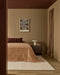 Hugo Floor Rug in Almond, at the foot of a bed with a terracotta bedspread and bedside table