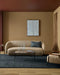 Hugo Floor Rug in Midnight, in a living room with a curved beige sofa and glass coffee table
