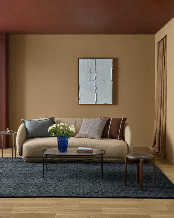 Hugo Floor Rug in Midnight, in a living room with a curved beige sofa, glass coffee table and flowers