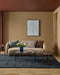 Hugo Floor Rug in Midnight, in a living room with a curved beige sofa, glass coffee table and flowers