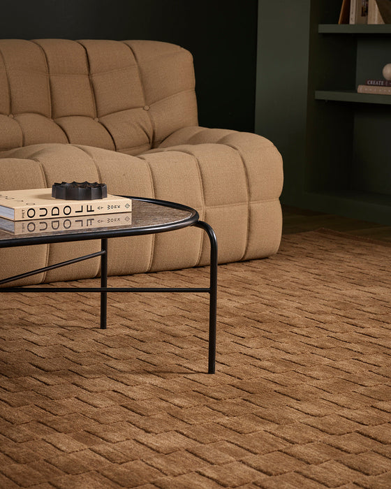 Hugo Floor Rug in Toffee, under a black framed glass coffee table beside a tan quilted sofa