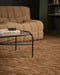 Hugo Floor Rug in Toffee, under a black framed glass coffee table beside a tan quilted sofa