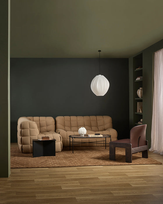 Hugo Floor Rug in Toffee, in a dark green living room with tan quilted sofas and a pendant light
