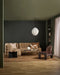 Hugo Floor Rug in Toffee, in a dark green living room with tan quilted sofas and patterned cushions