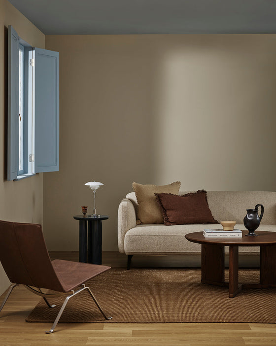 Linden Floor Rug in Ironbark, in a living room with a cream sofa, round timber table and leather sling chair