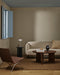 Linden Floor Rug in Ironbark, in a living room with a curved cream sofa, round timber table and sling chair