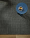 Linden Floor Rug in Petrol, seen from above with a blue side table and a coffee cup