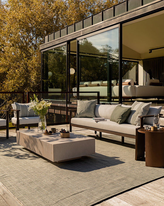 Lonsdale Floor Rug in Eucalyptus, on a timber deck with an outdoor sofa and concrete coffee table