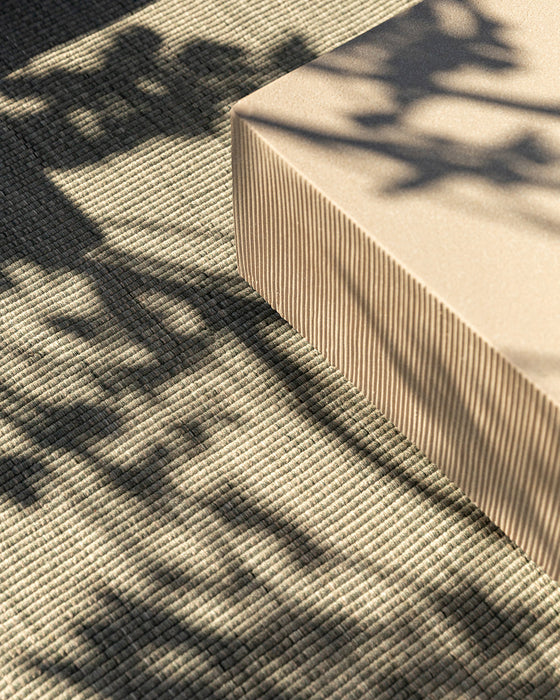 Lonsdale Floor Rug in Eucalyptus, close view beside a concrete block in dappled shade, showing the weave
