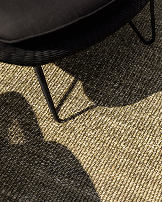 Lonsdale Floor Rug in Olive, close view under a black outdoor chair in sunlight, showing the weave