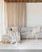Maya Floor Rug in Oatmeal, in a living room with a pale blue sofa and round timber coffee tables