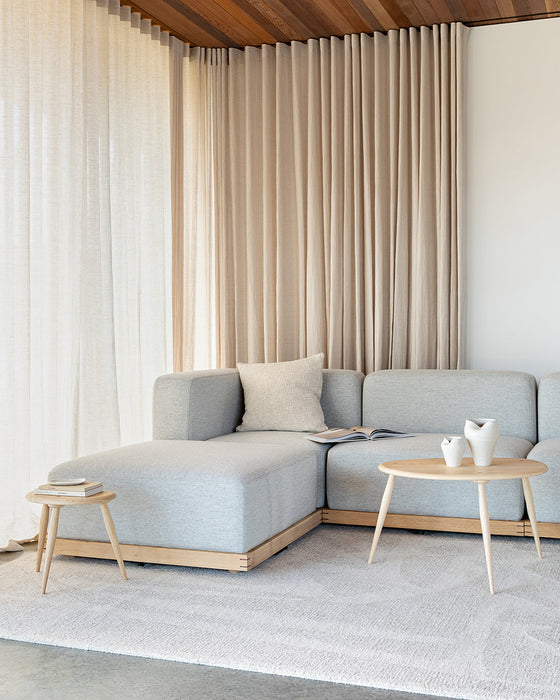 Maya Floor Rug in Oatmeal, in a living room with a pale blue modular sofa and timber side tables