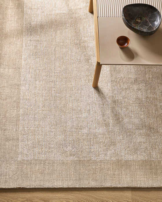 Mayfair Floor Rug in Abalone, seen from above under a timber side table, showing the bordered texture