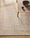 Mayfair Floor Rug in Abalone, seen from above under a timber side table, showing the bordered texture