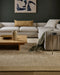 Mayfair Floor Rug in Wheat, under a low timber coffee table beside a cream sectional sofa