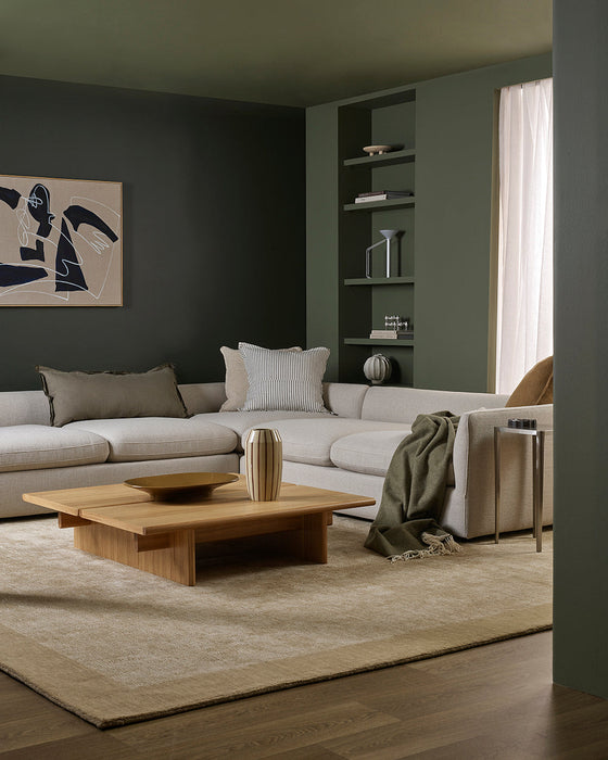 Mayfair Floor Rug in Wheat, in a green-walled living room with a cream sectional and timber coffee table