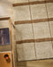 Mesa Floor Rug in Camel, seen from above beside a timber side table, showing the stripe pattern