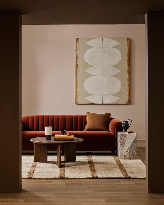 Mesa Floor Rug in Camel, in a living room with a rust velvet sofa and round timber coffee table