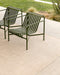 Lonsdale Floor Rug in Almond, on a concrete patio under two green metal outdoor chairs