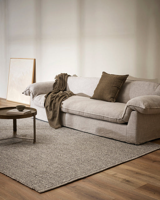 Nebraska Floor Rug in Ash, in a living room with a linen sofa and round dark side table
