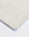 Nebraska Floor Rug in Natural White, close-up of a corner showing the edge and wool and viscose pile