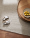 Nebraska Floor Rug in Natural White, seen from above beside a timber tray table and white slides