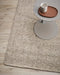 Nebraska Floor Rug in Pebble, close up beside a grey side table, showing the chunky weave