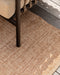 Ormond Floor Rug in Biscotti, close up under an outdoor chair leg on a timber deck, showing the weave