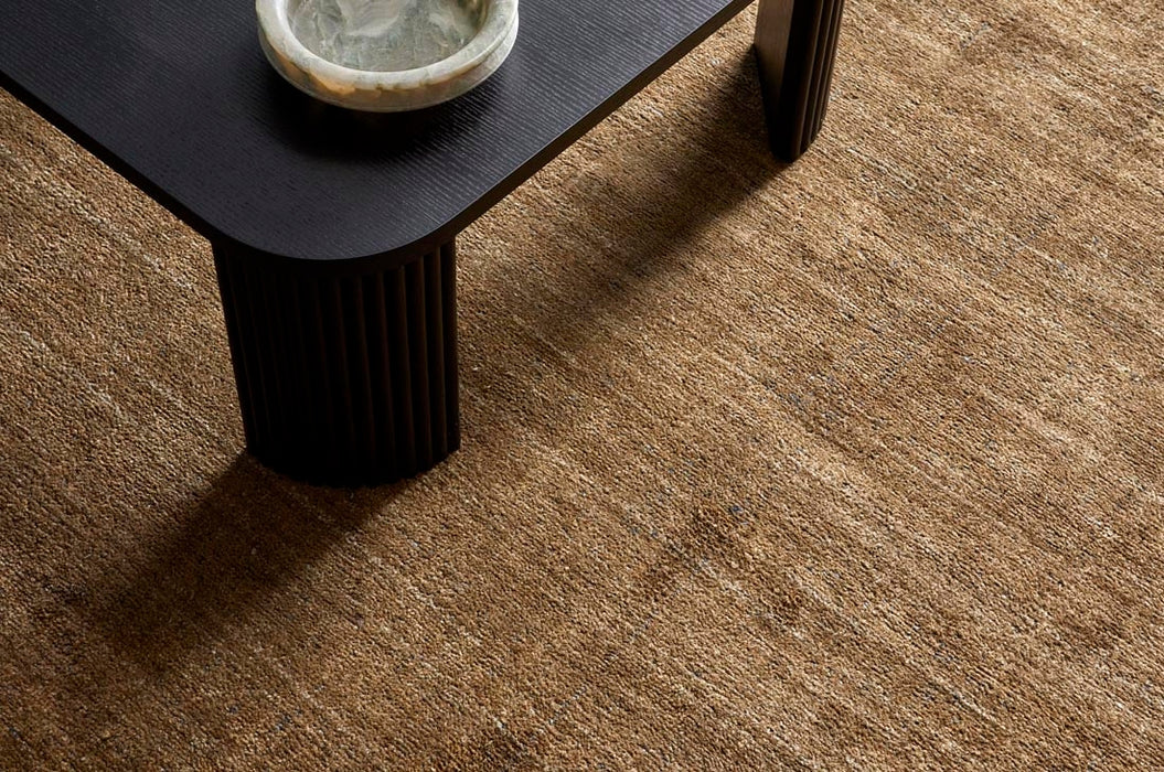 Tepih Dune Rug in Olive, seen from above under a black fluted side table