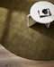 Sandringham Round Floor Rug in Moss, seen from above under a white stone side table, showing the pile