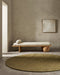 Sandringham Round Floor Rug in Moss, in a minimal room in front of a timber daybed with a bolster